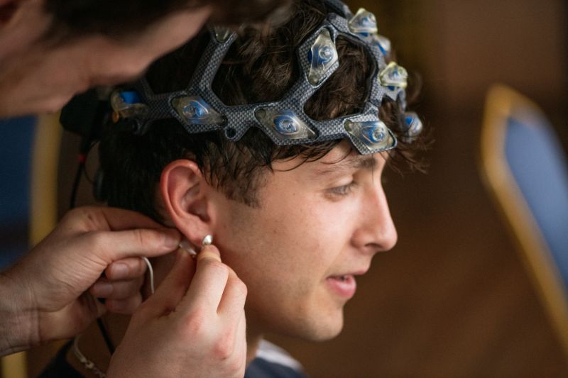 A technician fits a gel-free EEG brain mapping headset on a young man before his scan