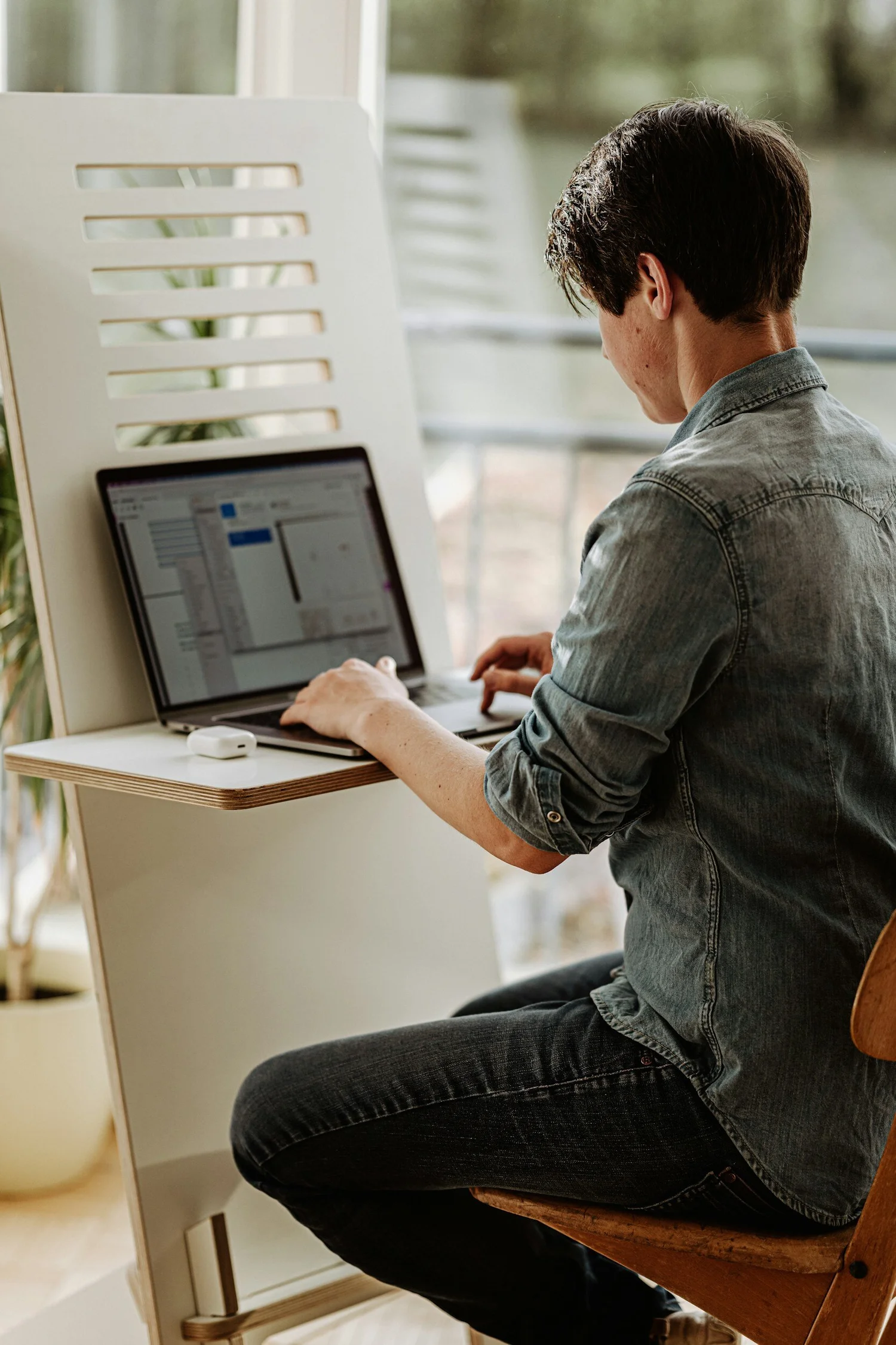 A person working at a laptop at a desk, the kind of long sitting that tightens hips and strains the low back